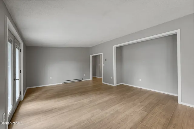 a view of an empty room with wooden floor and a window