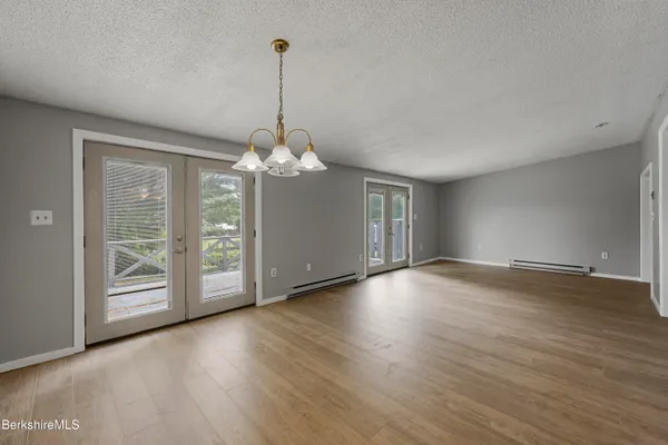 a view of a room with wooden floor chandelier and windows