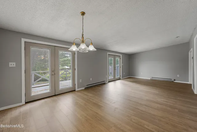 a view of a room with wooden floor chandelier and windows