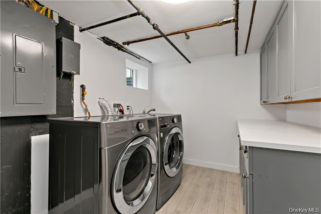9 Lyons Place New Rochelle, NY 10801 - Photo 14 of 20 Laundry room featuring electric panel, light wood-style floors, independent washer and dryer, and cabinet space