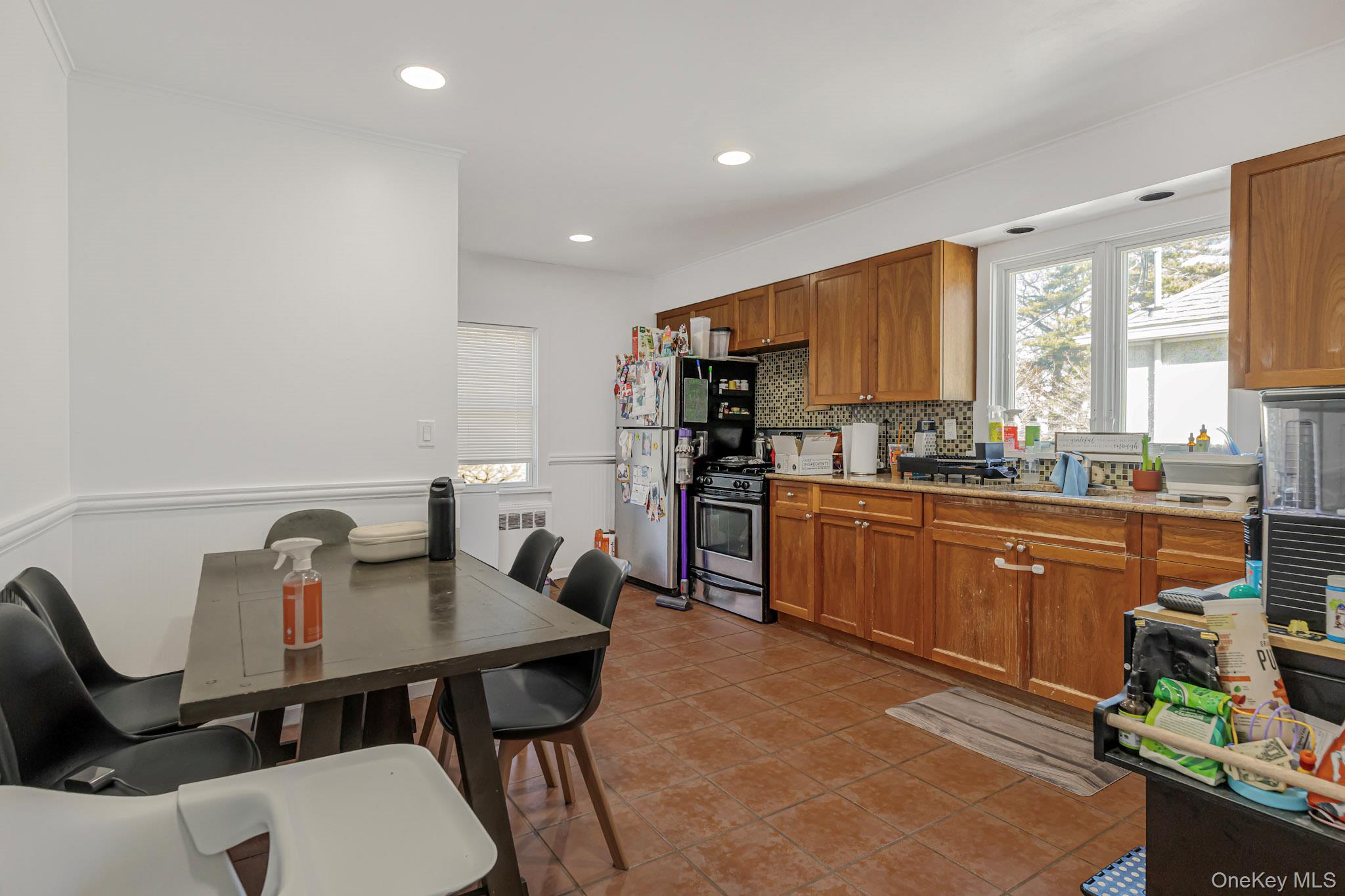 9 Lyons Place New Rochelle, NY 10801 - Photo 18 of 20 Kitchen with brown cabinets, appliances with stainless steel finishes, tasteful backsplash, recessed lighting, and light tile patterned flooring