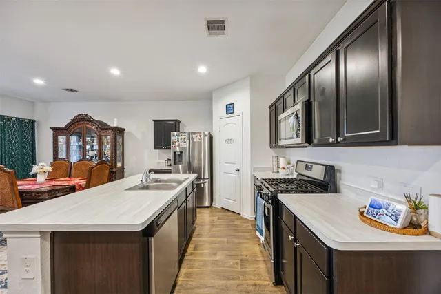 a kitchen with stainless steel appliances granite countertop a stove a sink dishwasher and a refrigerator with wooden floor