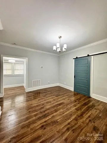 a view of an empty room with window and chandelier fan
