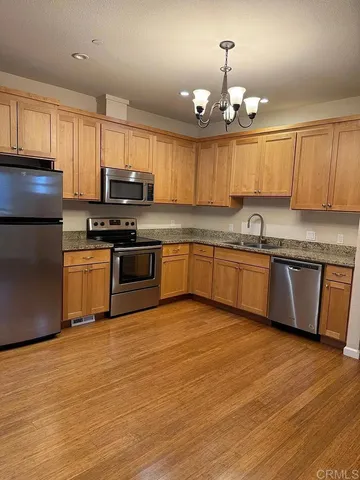 a kitchen with stainless steel appliances granite countertop a sink a stove a refrigerator cabinets and wooden floor