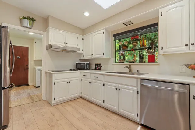 a kitchen with white cabinets and window