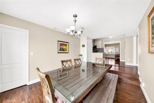 a dining room with wooden floor a chandelier a wooden table and chairs