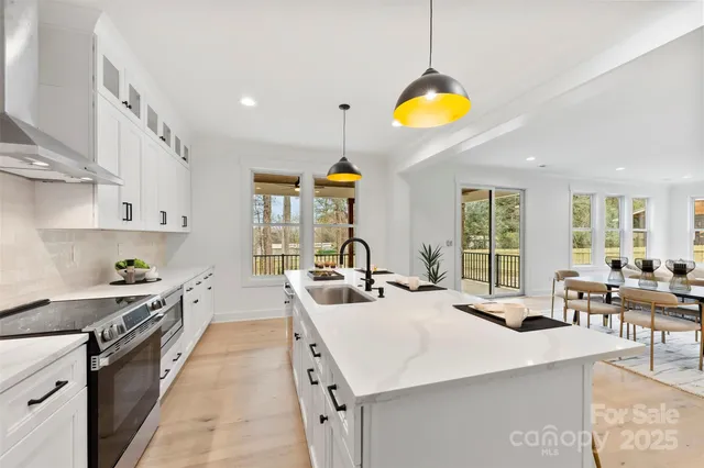 a large kitchen with stainless steel appliances granite countertop a sink a stove and a wooden floors