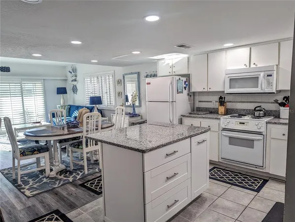 a kitchen with kitchen island granite countertop a sink cabinets and stainless steel appliances