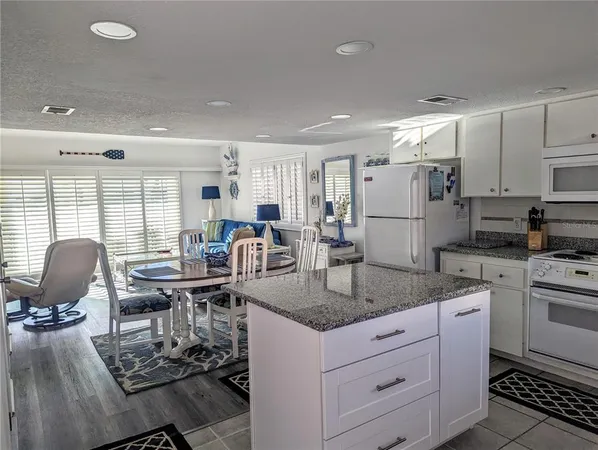 a kitchen with stainless steel appliances granite countertop a stove top oven a sink dishwasher a dining table and chairs with wooden floor