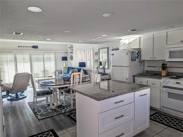 a kitchen with stainless steel appliances granite countertop a stove top oven a sink dishwasher a dining table and chairs with wooden floor