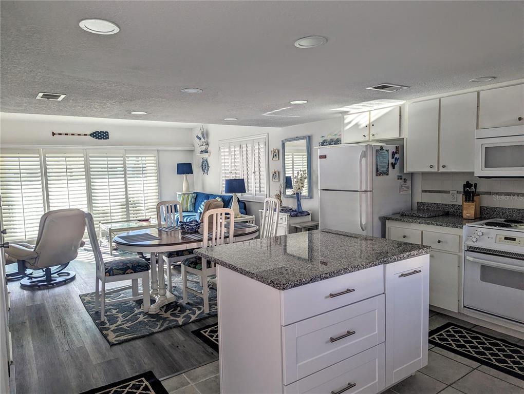 815 Ocean Shore Boulevard, Unit 11A Ormond Beach, FL 32176 - Photo 3 of 10 a kitchen with stainless steel appliances granite countertop a stove top oven a sink dishwasher a dining table and chairs with wooden floor