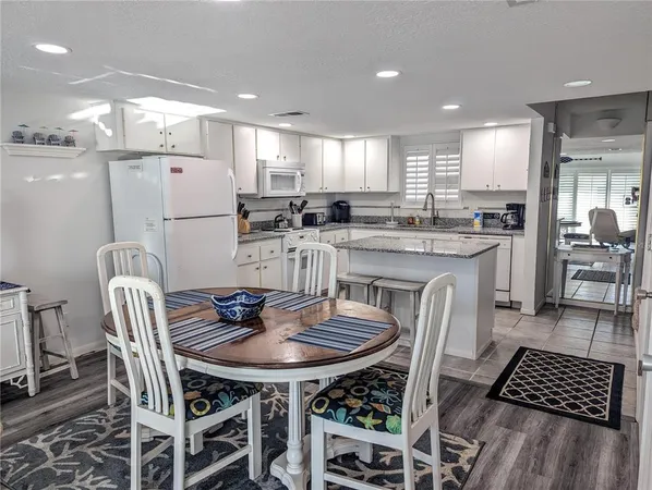 a kitchen with a dining table chairs and white appliances
