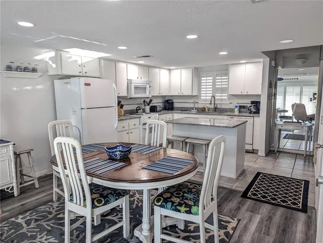 a kitchen with a dining table chairs and white appliances