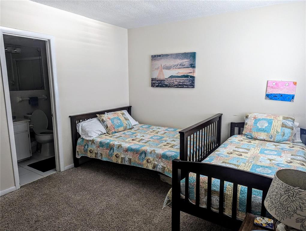 815 Ocean Shore Boulevard, Unit 11A Ormond Beach, FL 32176 - Photo 5 of 10 a bedroom with a bed a table and chair