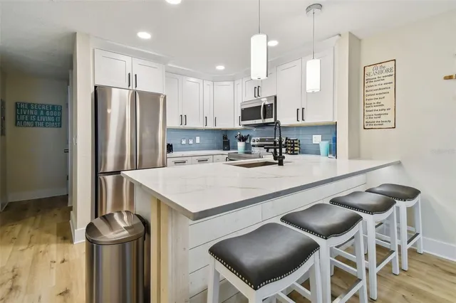 a kitchen with stainless steel appliances kitchen island a table chairs sink and cabinets