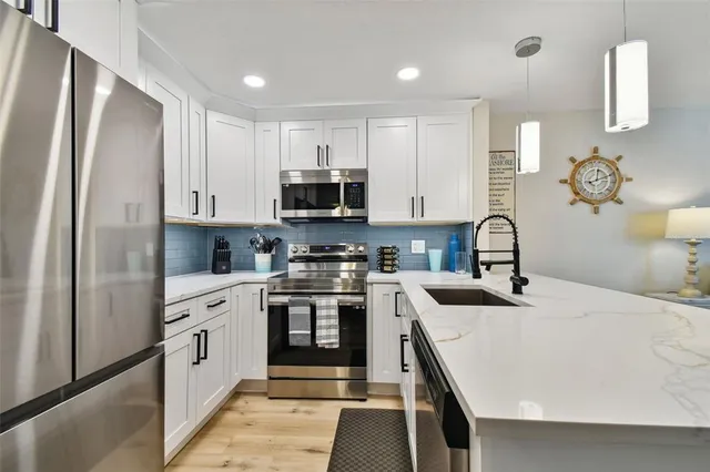 a kitchen with stainless steel appliances granite countertop a sink a stove a refrigerator and cabinets