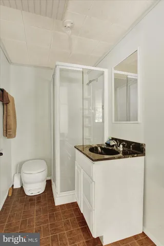 a bathroom with a granite countertop sink a toilet a mirror and shower