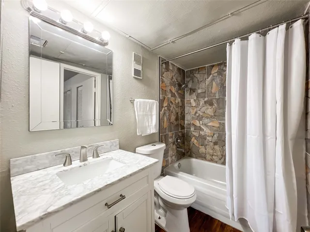 a bathroom with a granite countertop sink toilet mirror and shower