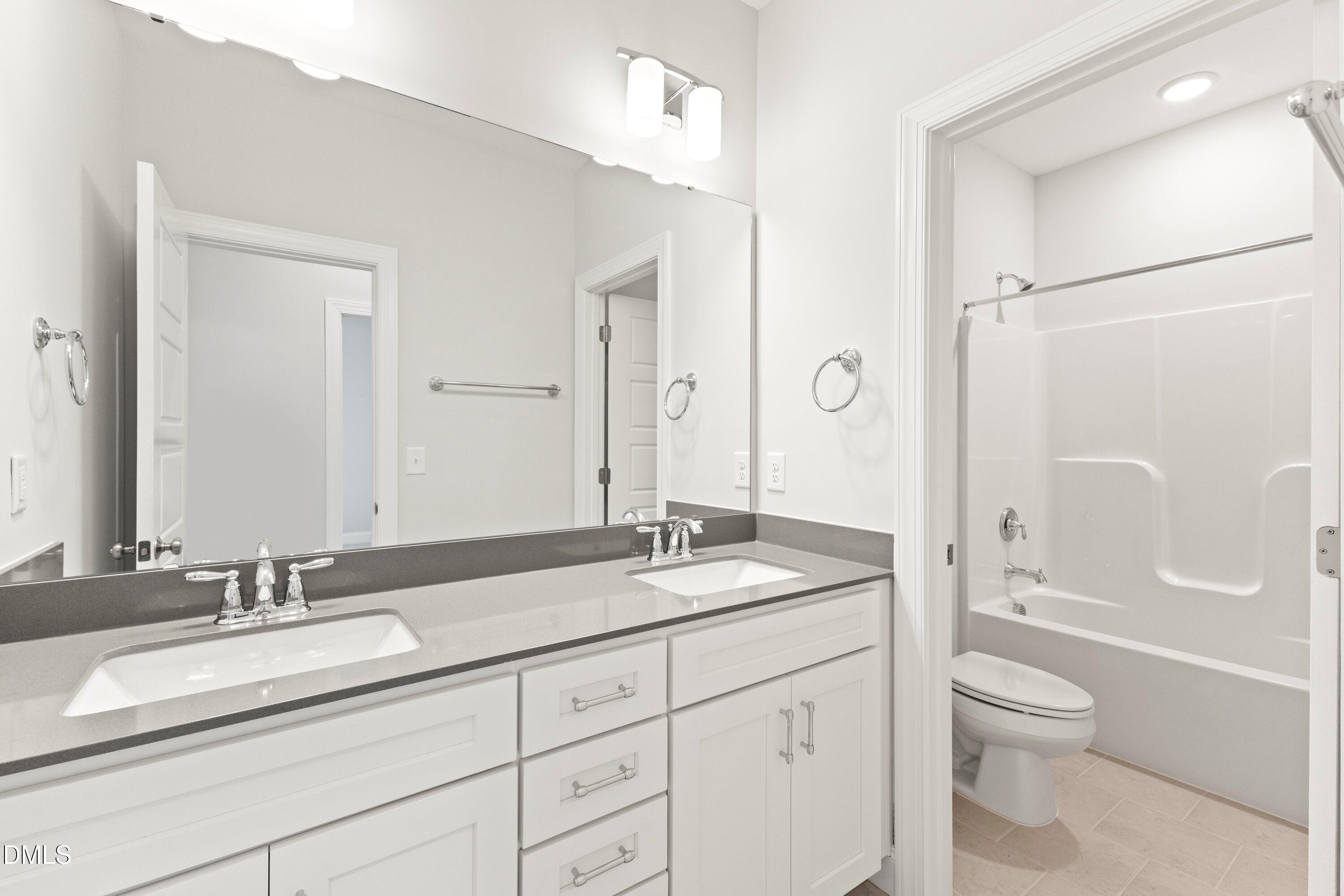 7 East Victoria Ridge Drive, Unit 16 Selma, NC 27576 - Photo 44 of 45 a bathroom with a granite countertop sink toilet a large mirror a shower and a bathtub