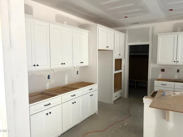 a view of an empty room with wooden floor fireplace and a window