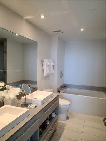 a bathroom with a sink a toilet and a large mirror