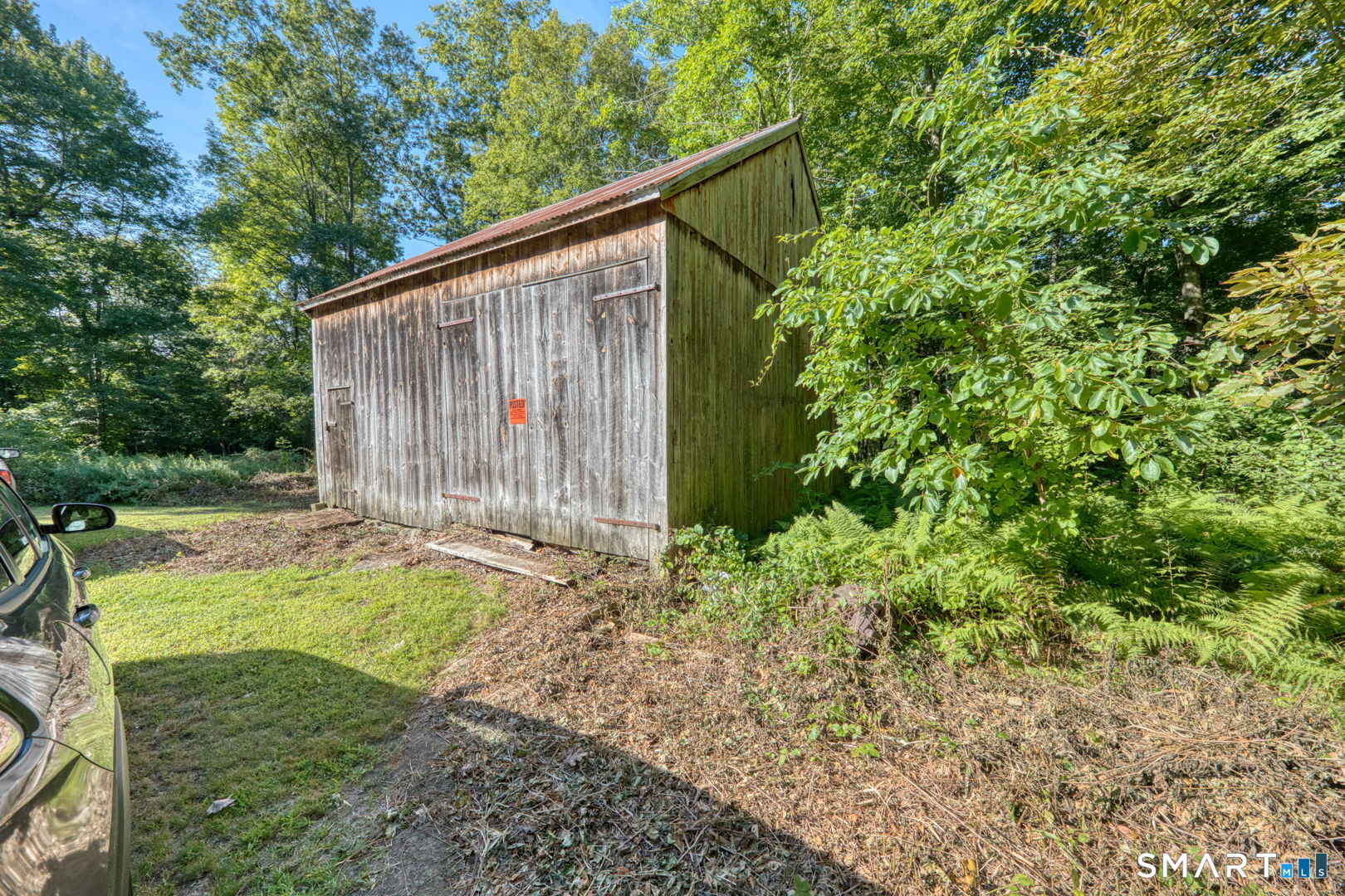 335 Old Post Road Tolland, CT 06084 - Photo 8 of 13 Side view of the existing barn set against a natural wooded backdrop.