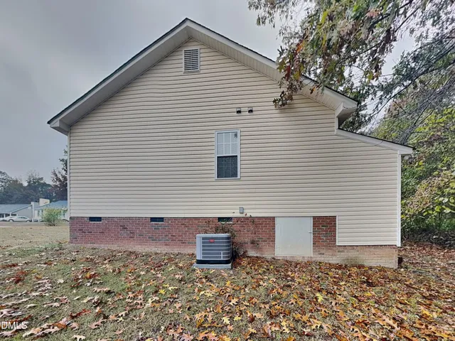 a view of a white house with a small yard and large tree
