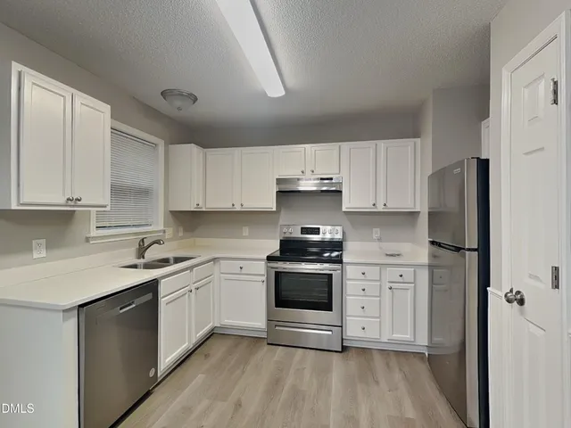 a kitchen with cabinets stainless steel appliances a sink and wooden floor