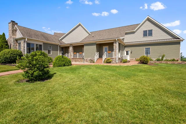 a view of a house with a big yard plants and large tree