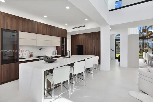 a kitchen with stainless steel appliances a sink dishwasher a stove top oven a refrigerator with wooden cabinets and floor