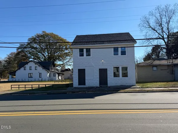 a front view of a house with a garden and parking area