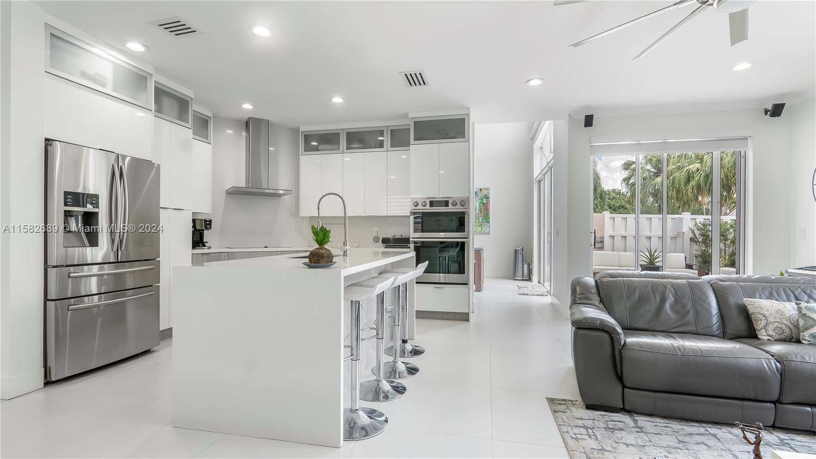 a kitchen with stainless steel appliances kitchen island granite countertop a refrigerator and a couch