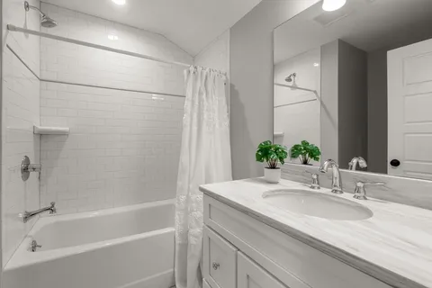 a bathroom with a granite countertop sink and a bathtub