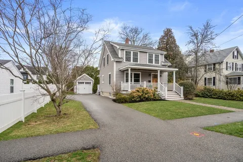 a front view of a house with a garden and trees