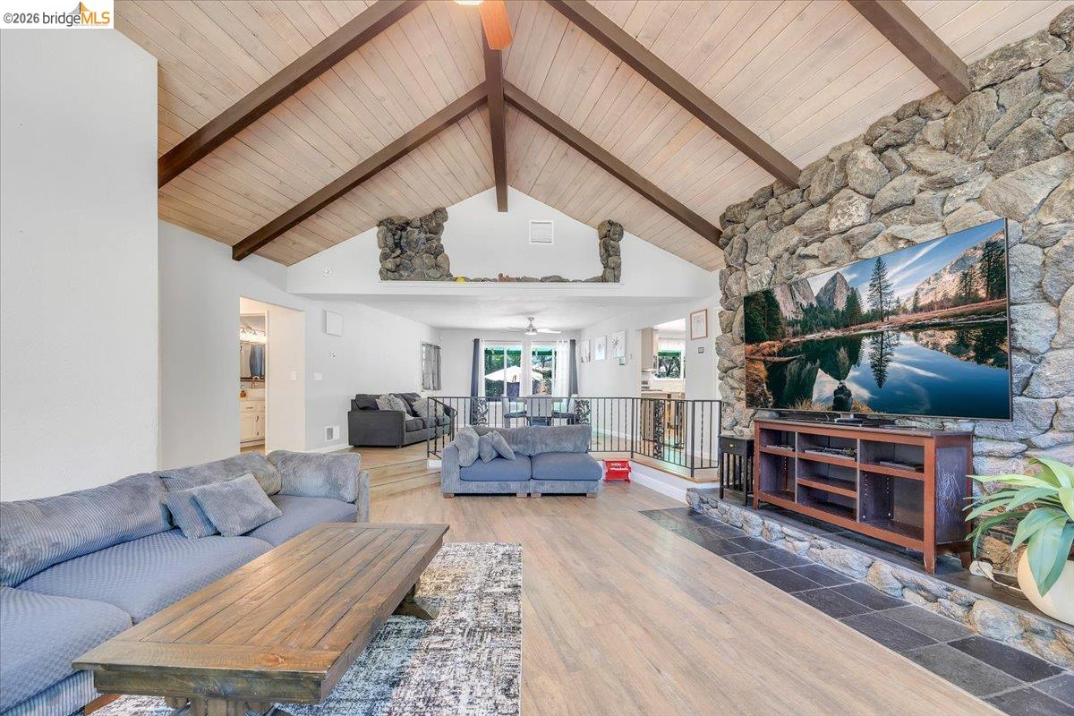 8733 Fraguero Road Sonora, CA 95370 - Photo 27 of 73 Vaulted wood-plank ceiling with exposed beams, stone accent wall, wood-finish flooring, and an open concept layout with a railing overlooking a lower level