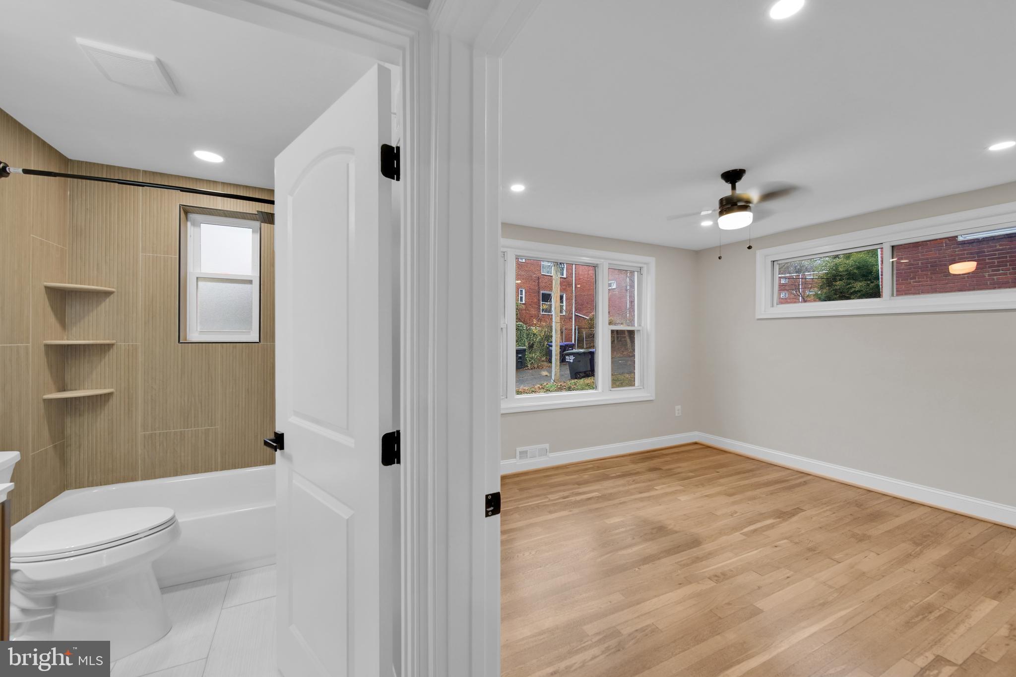119 Victor Street Northeast, Unit 2 Washington, DC 20011 - Photo 11 of 25 a bathroom with a granite countertop sink a toilet a window and shower