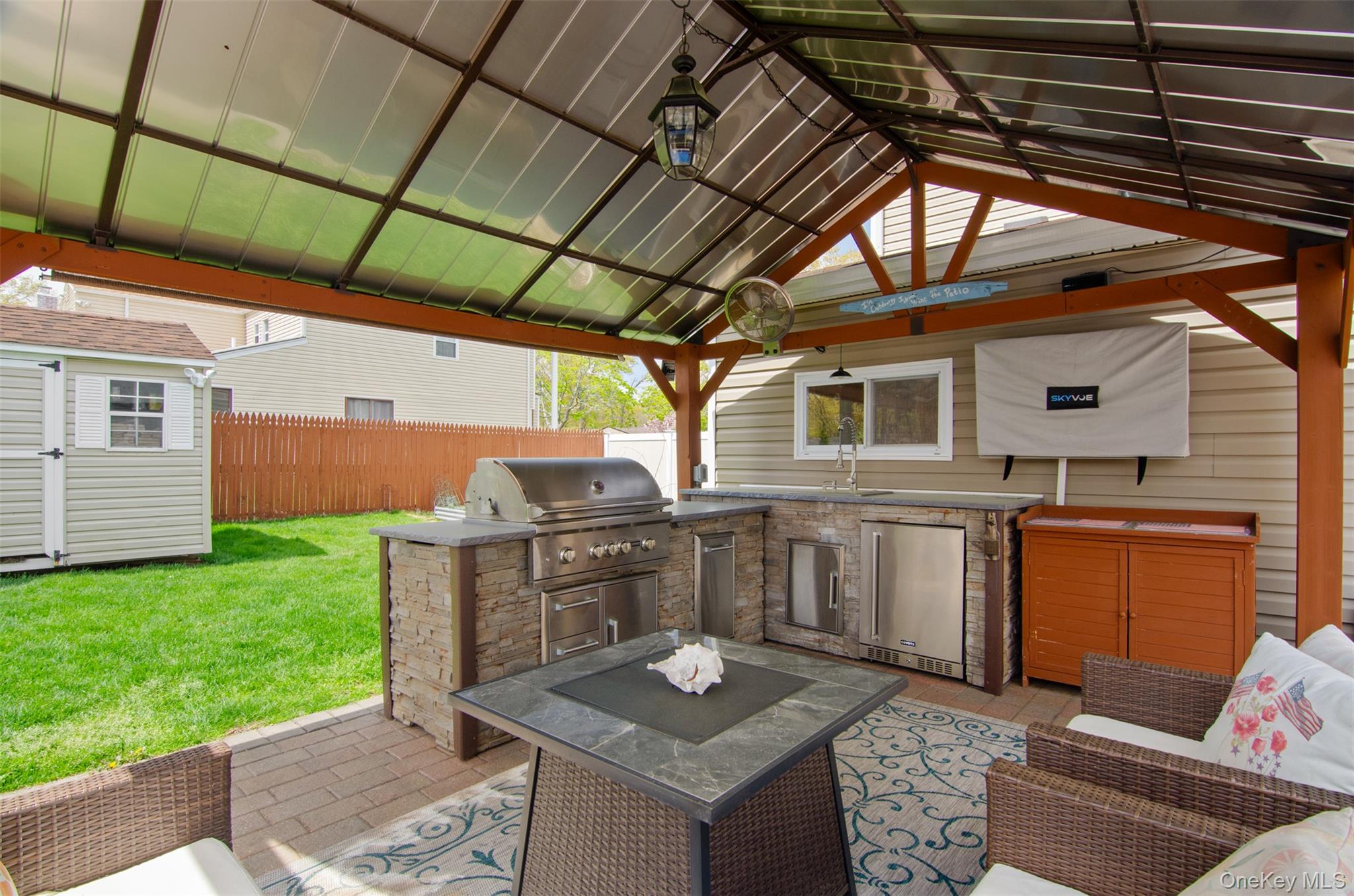 18 Calico Tree Lane Coram, NY 11727 - Photo 34 of 35 This outdoor kitchen has a grill , refrigerator, garbage can, storage and a set up for a TV