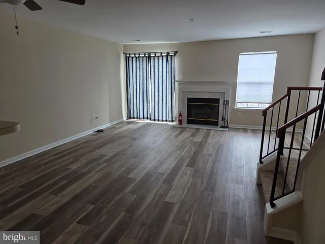 a view of an empty room with wooden floor fireplace and a window
