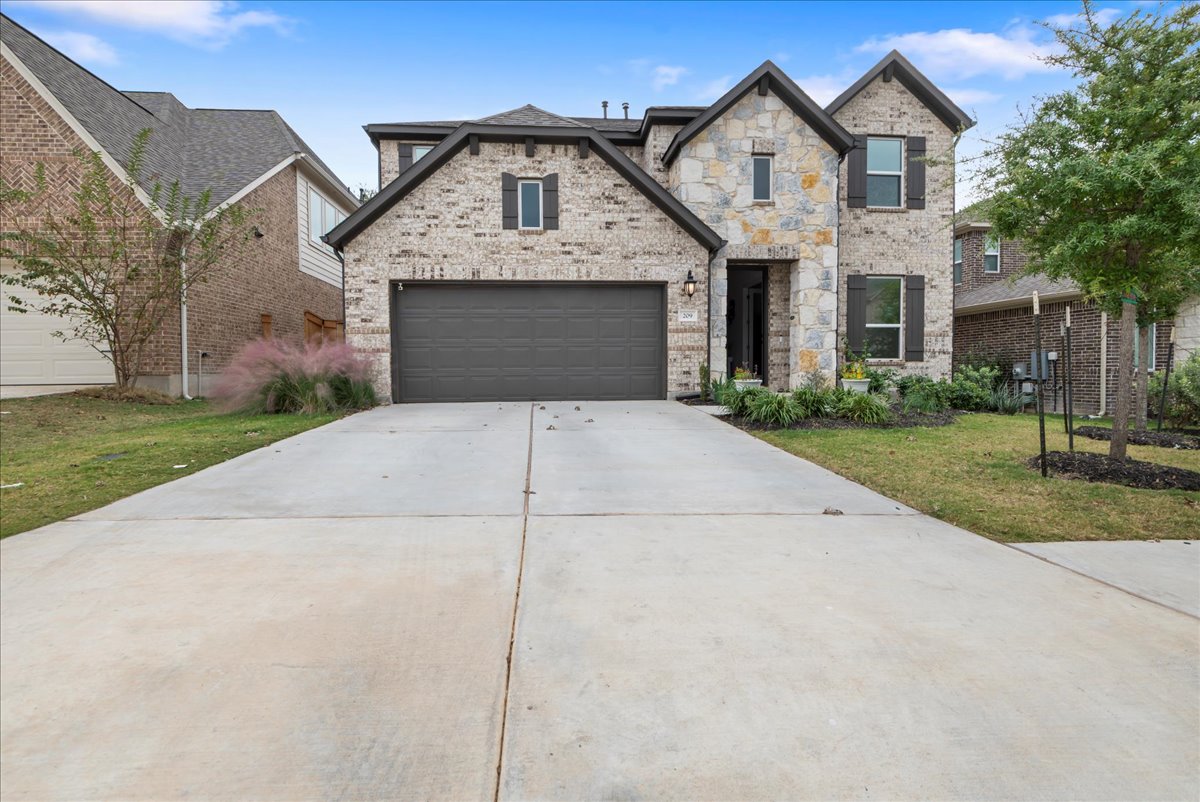 French country home with brick siding, concrete driveway, and a front yard
