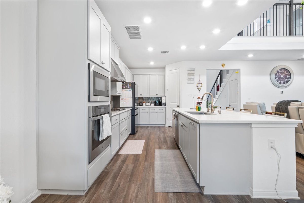 209 Terra Mnr Trail Georgetown, TX 78628 - Photo 13 of 40 Kitchen featuring stainless steel appliances, an island with sink, dark wood-style flooring, recessed lighting, and white cabinetry