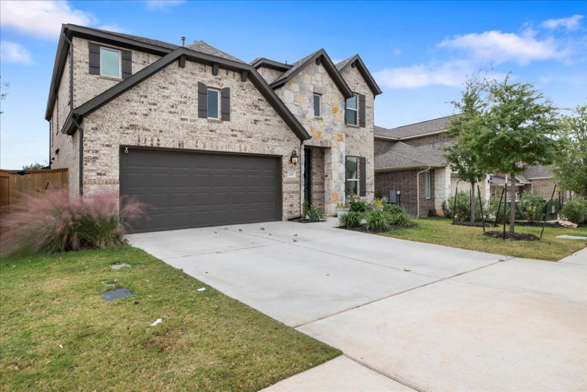 209 Terra Mnr Trail Georgetown, TX 78628 - Photo 2 of 40 French country inspired facade with driveway, brick siding, a garage, and a front lawn