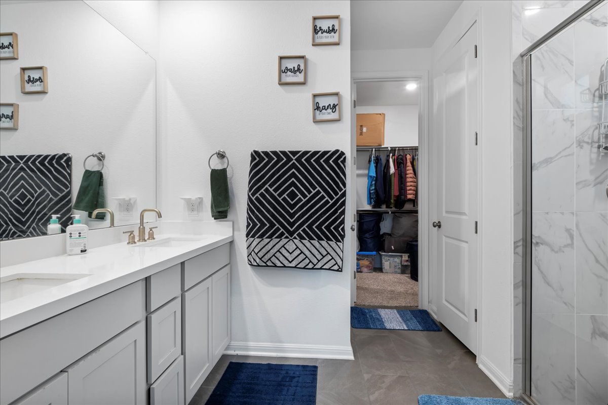 209 Terra Mnr Trail Georgetown, TX 78628 - Photo 19 of 40 Bathroom featuring double vanity, a marble finish shower, and a walk in closet