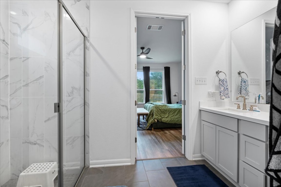 209 Terra Mnr Trail Georgetown, TX 78628 - Photo 20 of 40 Ensuite bathroom featuring vanity, a marble finish shower, dark tile patterned flooring, and a ceiling fan
