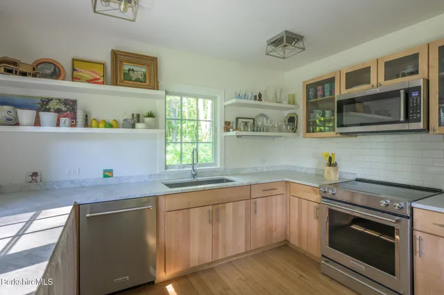 a kitchen with stainless steel appliances granite countertop a sink and a stove next to a window