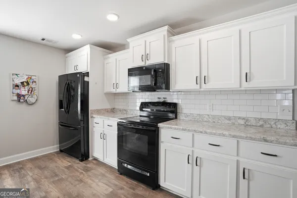 a room with granite countertop a sink dishwasher a dining table and chairs with wooden floor