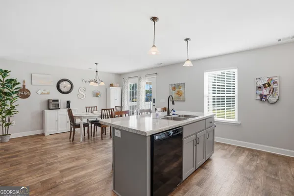 a kitchen with stainless steel appliances granite countertop a dining table chairs refrigerator and microwave