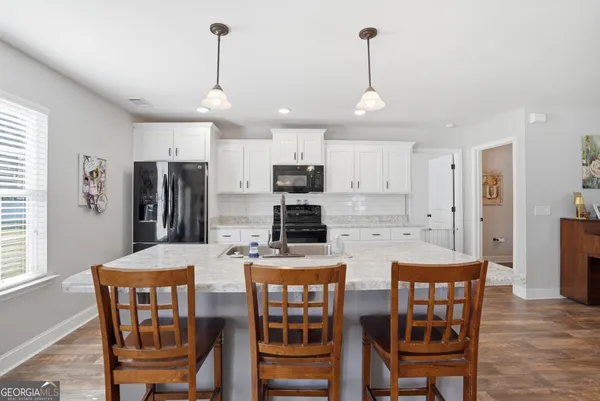 a kitchen with stainless steel appliances granite countertop a stove a refrigerator a kitchen island a dining table and chairs