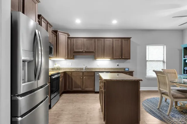 a kitchen with stainless steel appliances granite countertop a refrigerator a stove a sink and a microwave