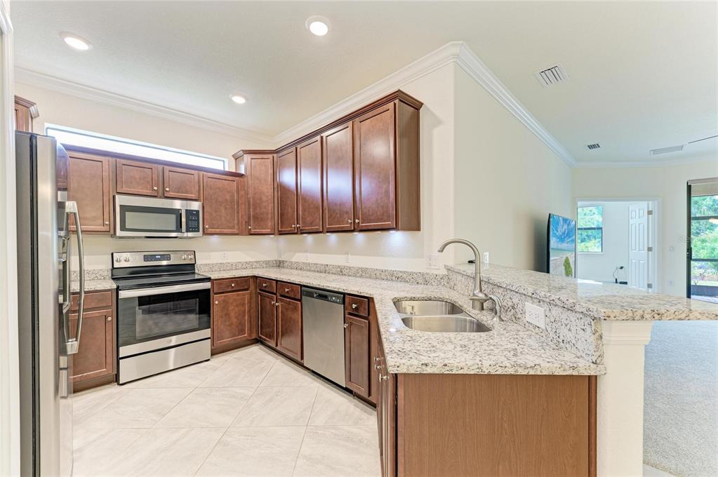 12434 Amica Loop Venice, FL 34293 - Photo 13 of 74 a kitchen with stainless steel appliances granite countertop a sink and stove top oven