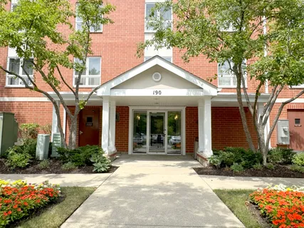 a view of a house with brick walls plants and large trees